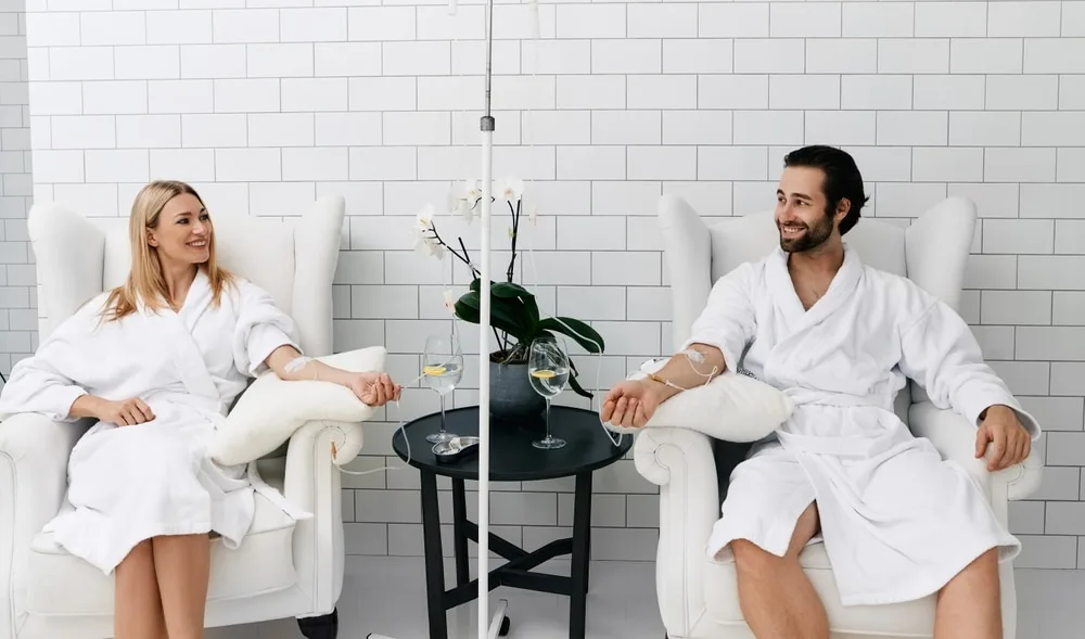 Two people in robes receiving IV infusions in a treatment lounge