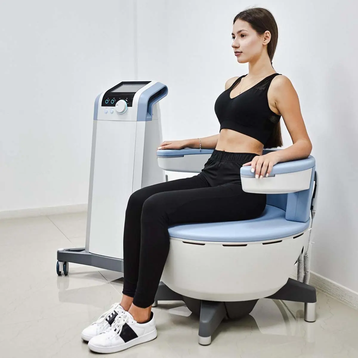 A clothed patient seated on a pelvic floor strengthening chair