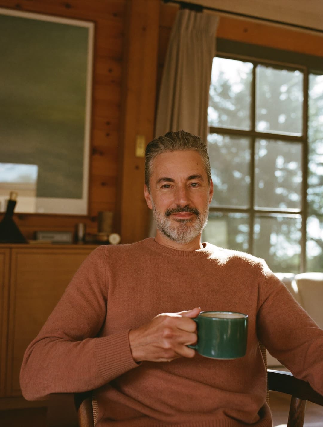 Relaxed man in his fifties with a warm drink in a sunlit room